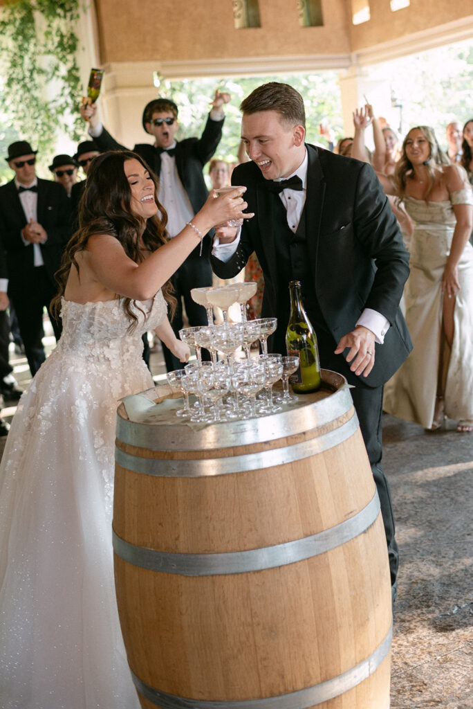 Bride and groom pouring Champagne over their champagne tower at wedding in Gervasi Vineyard | J. Lynne Photography