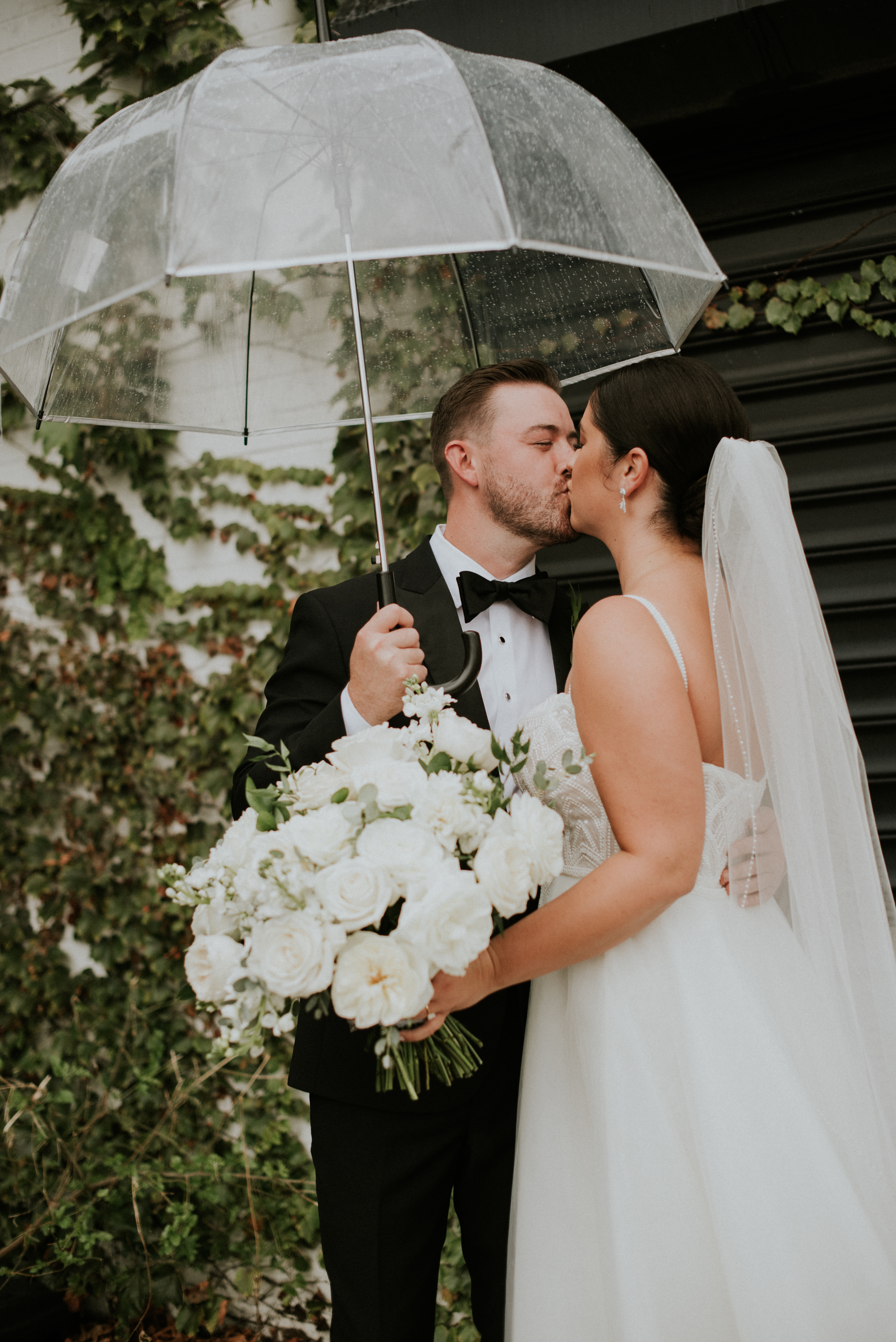Bride and groom kissing outside under a clear umbrella in light snow in Ohio | J. Lynne Photography