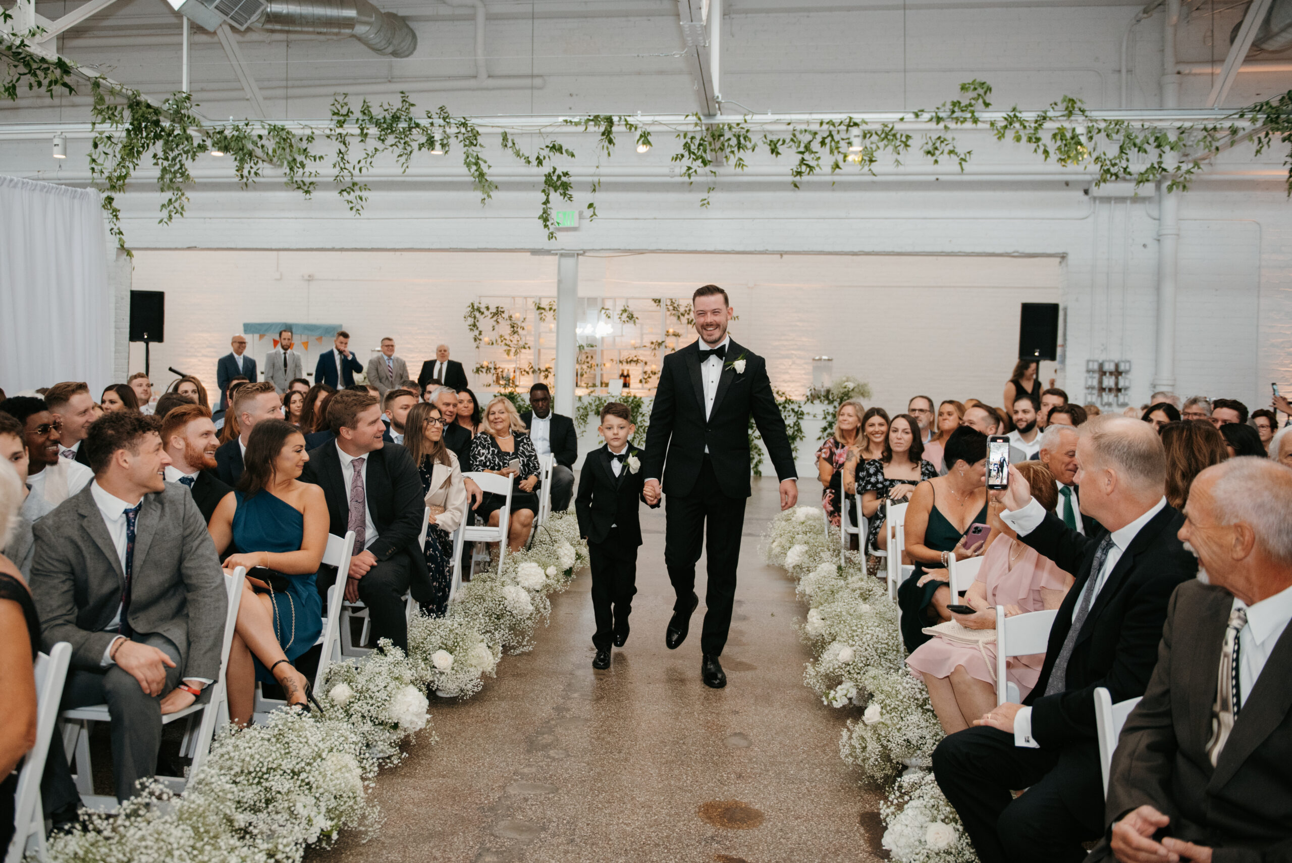 Father walking with his young son to wait for his bride at the end of the wedding aisle | J. Lynne Photography