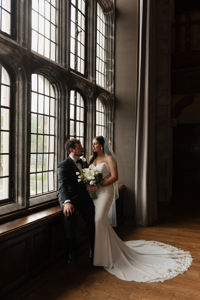 Couple taking first photos after wedding in front of historic floor to ceiling windows | J. Lynne Photography